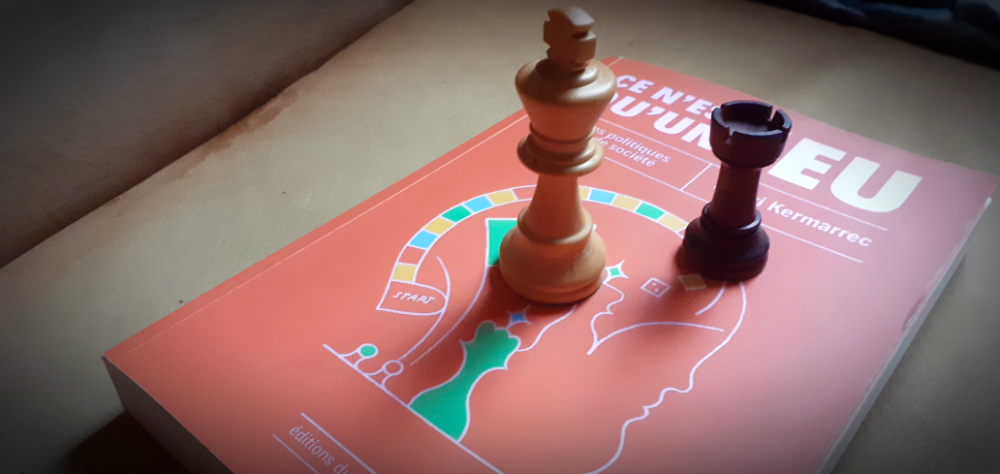 Le livre "Ce n'est qu'un jeu" sur lequel sont posés deux pièces d'échec : une noire et une blanche